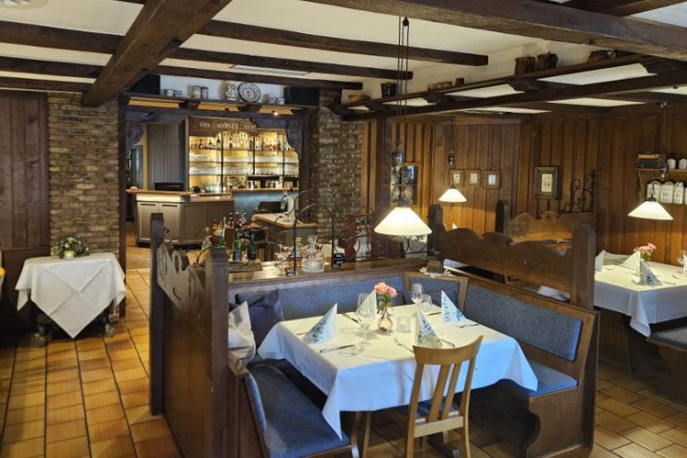 Gemütliches Restaurant mit Holzmöbeln und eingedeckten Tischen.