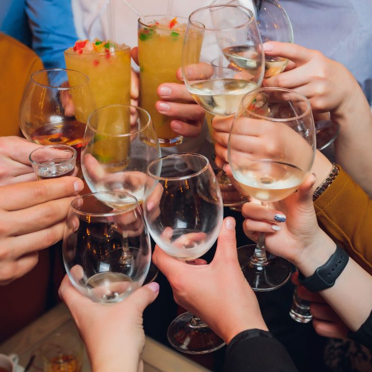 Viele Hände, die mit verschiedenen alkoholischen Getränken anstoßen.