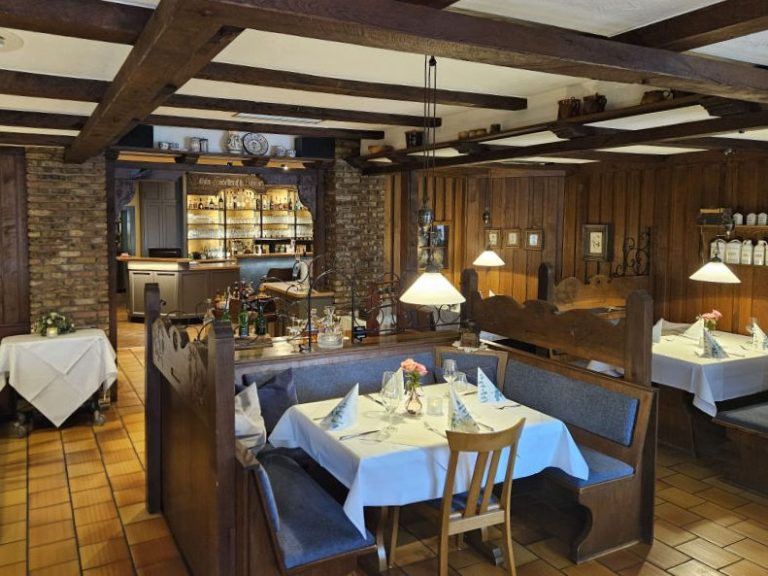 Blick auf ein uriges Restaurant mit Holzmöbeln, alten Deckenbalken und gemütlichen Nischen.
