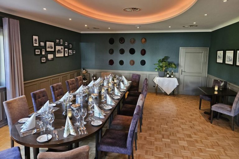 Eleganter, moderner Raum mit festlich gedeckter Tafel ohne Tischdecke und historischen Fotografien an den Wänden.