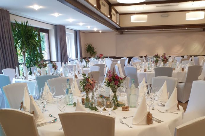 Elegant, gedeckte Tische mit Blumen und Dekoration in einem festlichen Saal.